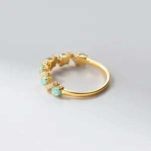 Detailaufnahme eines zarten vergoldeten Silber Opal Rings mit funkelnden Zirkoniasteinen.