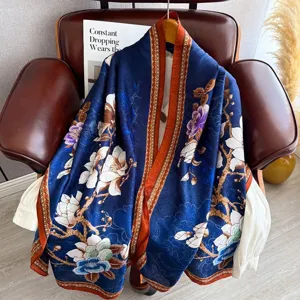 Detailed view of a long blue retro floral silk scarf draped elegantly over a leather chair.