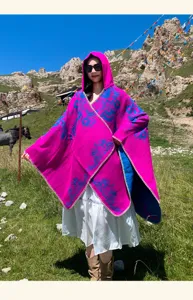 Vue détaillée d'un poncho à capuche ethnique, châle rose vif avec motif tribal bleu.