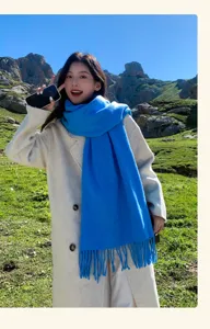Outdoor detail shot of a bright blue wool winter scarf with fringe, soft cozy warm neck wrap.