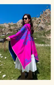 Gros plan du poncho à capuche ethnique présentant un tissu rose vif et des motifs bleus.