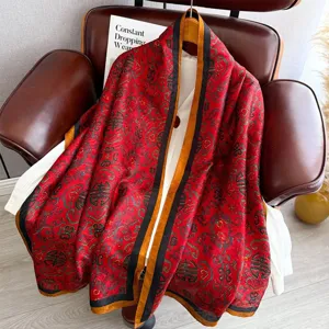Red retro patterned long silk scarf shawl, detailed view hanging on a leather chair.