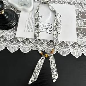 Close-up detail of retro black and white paisley silk scarf necklace with wooden bead accents.