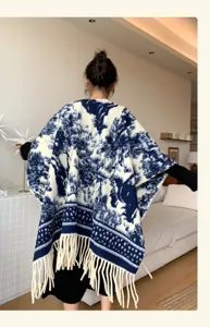 Women's blue and white landscape knitted cape shawl with cozy fringe hem for autumn stylish wear.