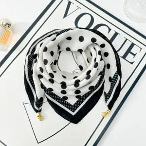 Detailed view of elegant black and white polka dot scarf with gold charm accents for daily wear.
