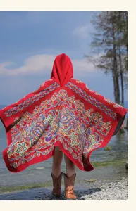 Detail view of the red hooded cape featuring intricate ethnic paisley patterns for autumn and winter.