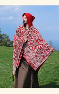 Detailed look at the red and grey patterned hooded cape, highlighting the tassels and texture.