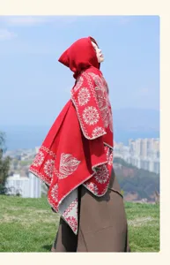 Detailed view of red hooded knitted poncho with ethnic pattern for stylish outdoor travel wear.