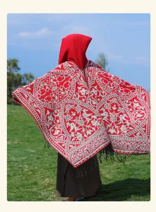 Detailed view of red ethnic style hooded poncho with intricate patterns and fringe hem.