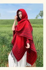 Vista detallada de un cómodo chal poncho con capucha rojo con borlas y patrón elegante.