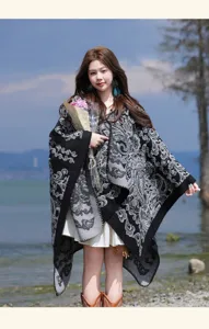 Detailed shot of woman wearing elegant black grey paisley patterned poncho cloak outdoor.