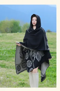 Detailed view of women's ethnic style hooded cashmere-like shawl cloak outdoors in green fields.