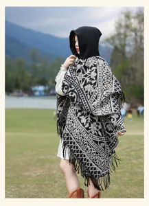 Detailed view of the ethnic style hooded cape shawl in black and white pattern with tassel trim.