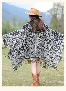 Back view detail of black and white vintage knit poncho with intricate tribal patterns and fringe.