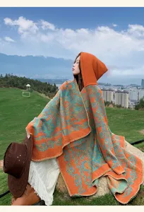 Detailed shot of an orange and teal hooded cloak, cozy knitted texture, outdoor scenic backdrop.