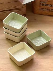 Detailed view of ceramic square dipping bowls with ripple texture in light green and cream.