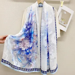 Detailed view of a elegant white silk scarf featuring blue and purple floral prints.