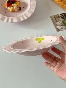 Pink ceramic plate detail view, cute ruffled edge tableware with red dots and hand-painted design.