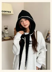 Detailed view of women's black knitted balaclava hooded scarf with white trim, cozy autumn wear.
