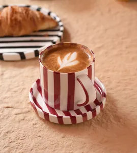 Conjunto de taza de café y platillo de cerámica a rayas retro, detalle de taza rojo y blanco.