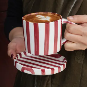 Juego de taza de cafe y platillo de ceramica con rayas rojas y blancas para uso diario.