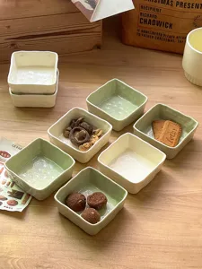 Detailed view of ceramic sauce dishes, featuring unique square shape and lifestyle table setting.