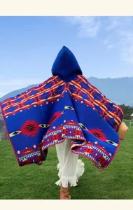 Ethnic style knitted hooded cape detail, colorful geometric pattern outerwear shot outdoors.