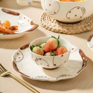 Détail d'ensemble de vaisselle en céramique avec motif de fraise mignon peint à la main.
