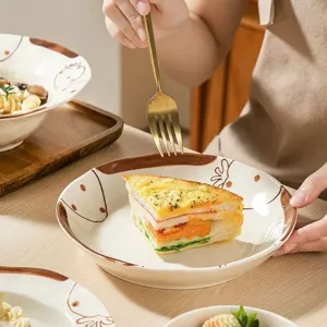Gros plan détaillé d'une jolie assiette en céramique avec motif de fraise et table.