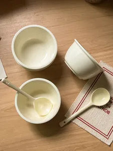 Ceramic bowl and spoon set lifestyle detail shot, minimalist style white table decor.