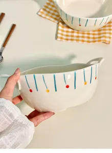 Close-up detail shot of ceramic double-eared bowl with hand-painted colorful stripes.