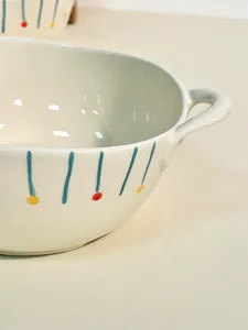 Close-up detail of ceramic dual-ear soup bowl with cute hand-painted blue stripes and dots.