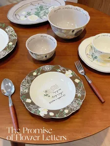 Gros plan sur l'ensemble d'assiettes et bols en céramique motif rose sur table.
