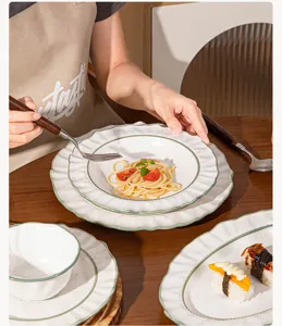 Detalle de plato de cerámica con borde verde elegante y textura jaspeada sobre la mesa.