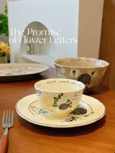 Vue détaillée d'un service d'assiettes et bols en céramique florale vintage sur table bois.