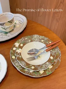 Détail de la vaisselle en céramique vintage avec assiettes florales et couverts en bois.