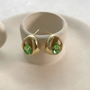 Nahaufnahme von grünen Kristall Tropfen Ohrringen in Goldton, filigranes Schmuckdetail.