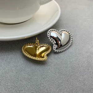 Vue détaillée de boucles d'oreilles cœur chic en or et argent avec bordure perlée.