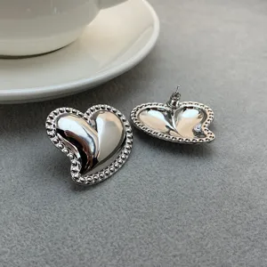 Boucles d'oreilles clous coeur argenté avec bordure perlée, bijou minimaliste chic.