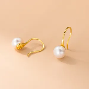 Primer plano de pendientes colgantes de perlas de agua dulce con diseño de metal curvo.