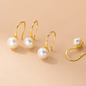 Primer plano detallado de pendientes de gancho de perlas de agua dulce de plata esterlina minimalista.