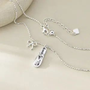 Gros plan détail du collier en argent avec pendentif chausson de danse et nœud délicat.