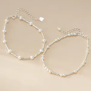 Detailaufnahme eines Sterling Silber und Perlen Stapelarmbands mit funkelnden Perlen.