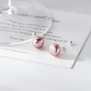 Detailaufnahme von eleganten rosa Süßwasserperlen-Ohrsteckern mit feinen Silberstiften.
