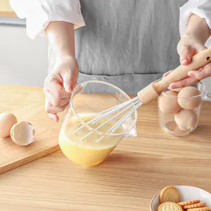 Misurino in plastica trasparente con scala e frusta con manico in legno per cottura e cucina.
