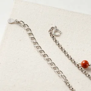 Vue détaillée de la chevillère en argent avec étiquette S925 et perle d'agate rouge.