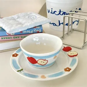 Ceramic bowl and plate set detail view, hand-painted blue stripes and cute apple pattern.
