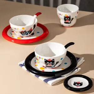 Joli service de vaisselle en céramique avec motif de chat noir, bols, assiettes et tasses.