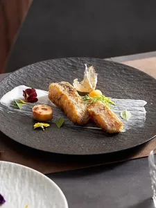 Detailed view of a black ceramic steak plate with elegant stone texture, perfect for fine dining.