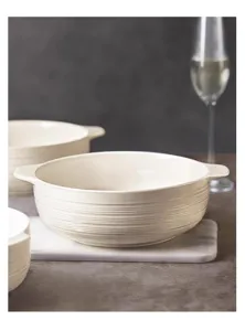 Close-up detail of white ceramic soup bowl with double handles and ribbed texture surface.